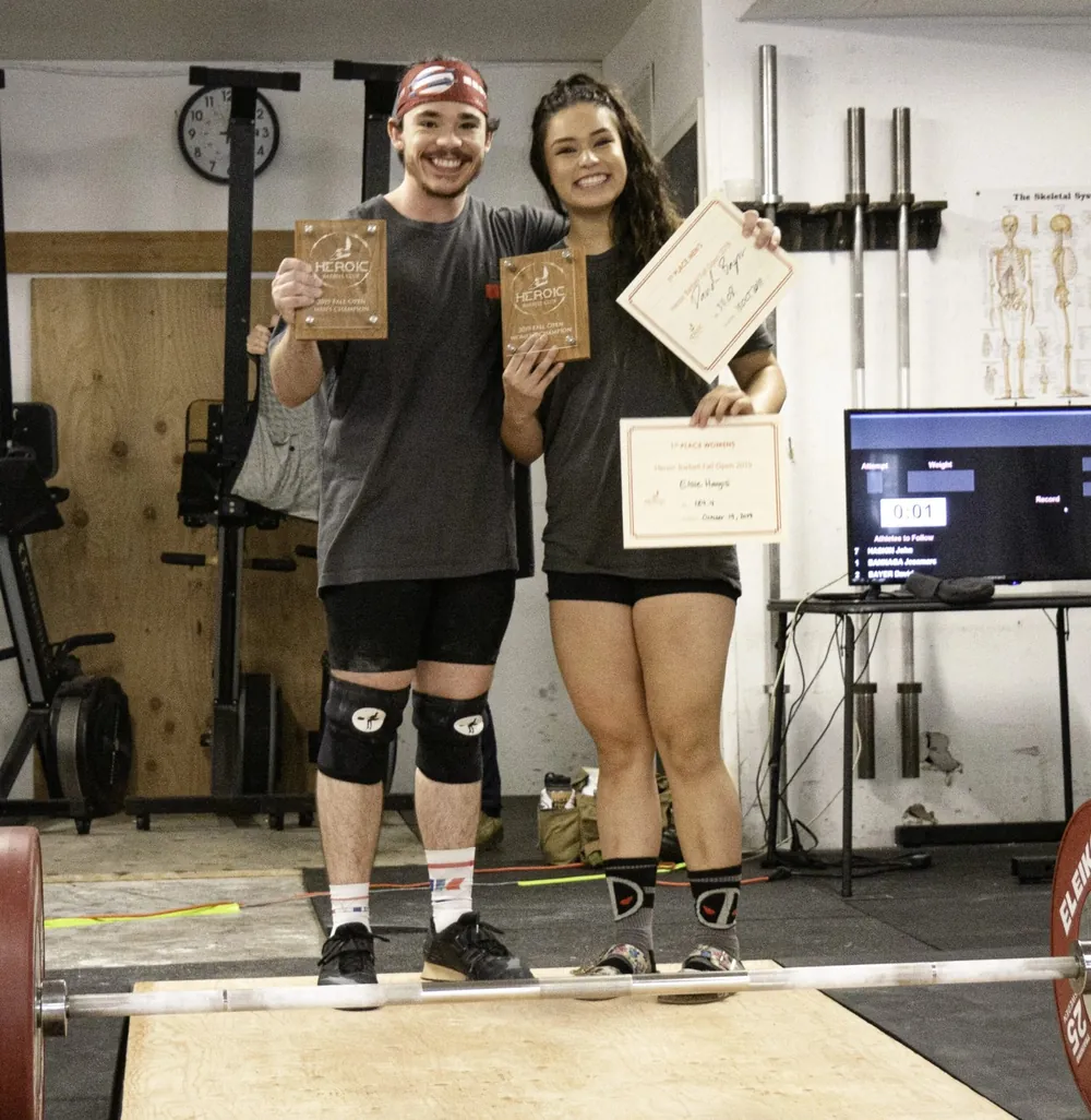 Coach David Bayer with athlete Elsie, both holding awards at a meet